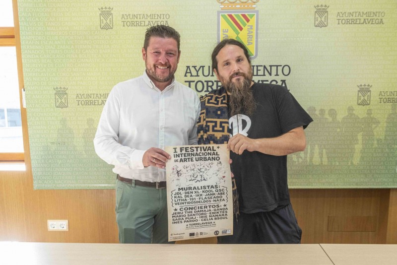 El concejal de Desarrollo Local de Torrelavega, Jesús Sánchez, acompañado de Daniel Revenga, de Mens Rea. Están sujetando el cartel del festival.