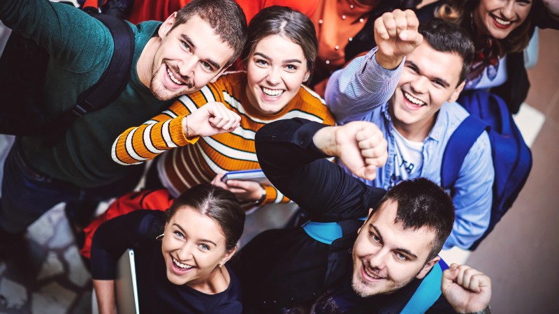 Grupo de jóvenes vistos desde arriba, mirando sonrientes hacia la cámara