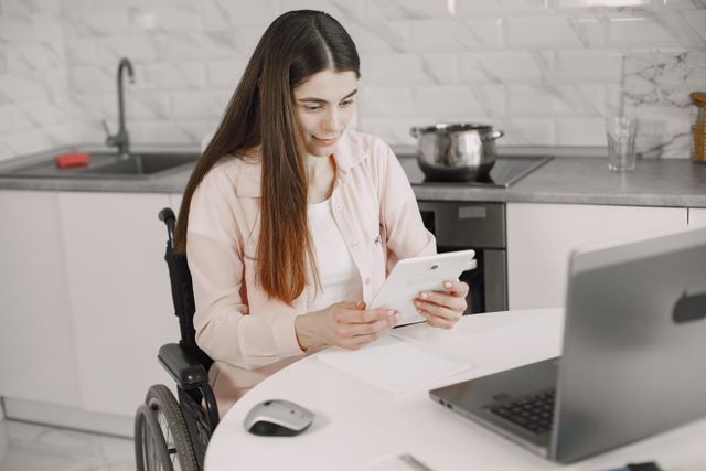 chica en silla de ruedas frente a mesa con port&aacute;til
