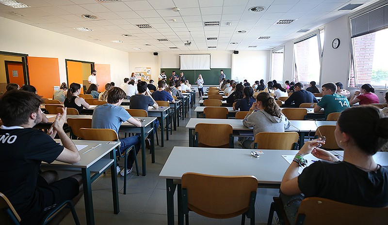 imagen de aula con alumnado en pupitres tomada desde el fondo con encerado verde al frente