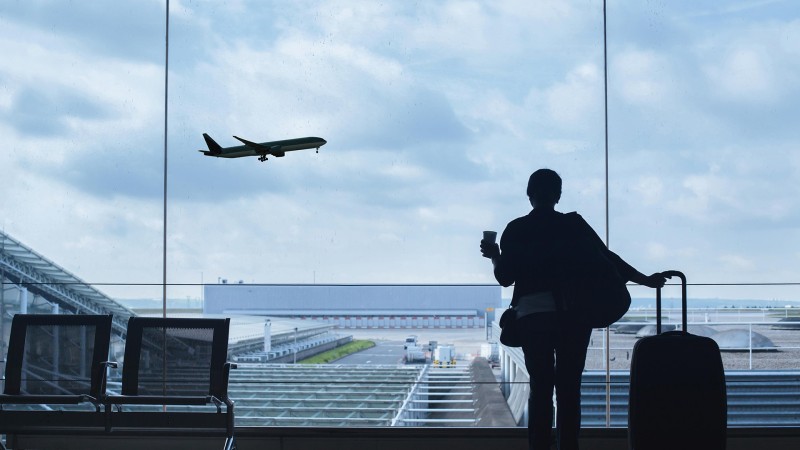 Una persona de espaldas a contraluz en la ventana de un aeropuerto