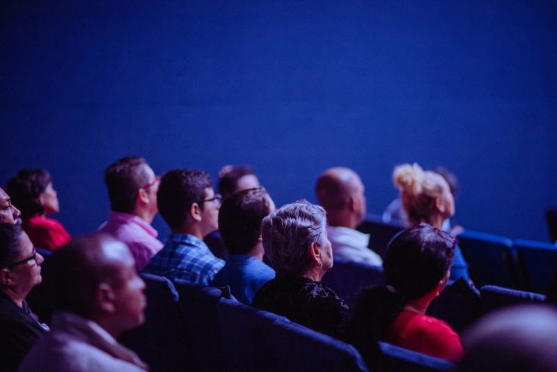 público en un foro a oscuras mirando hacia el escenario (luz azul)