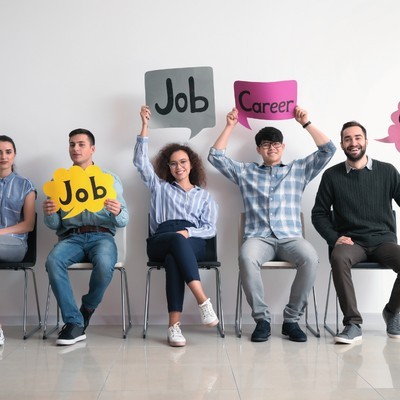 jovenes sentados con carteles de empleo